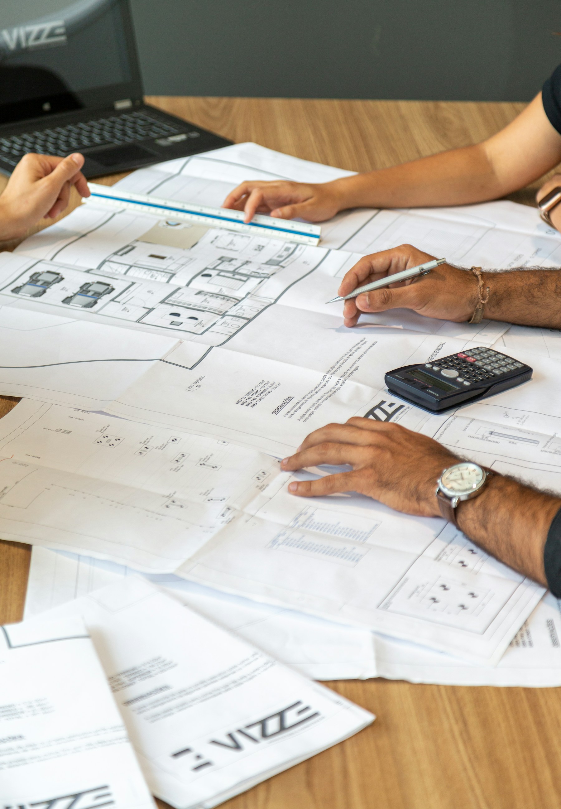 Two practitioners reviewing architectural blueprints on a desk