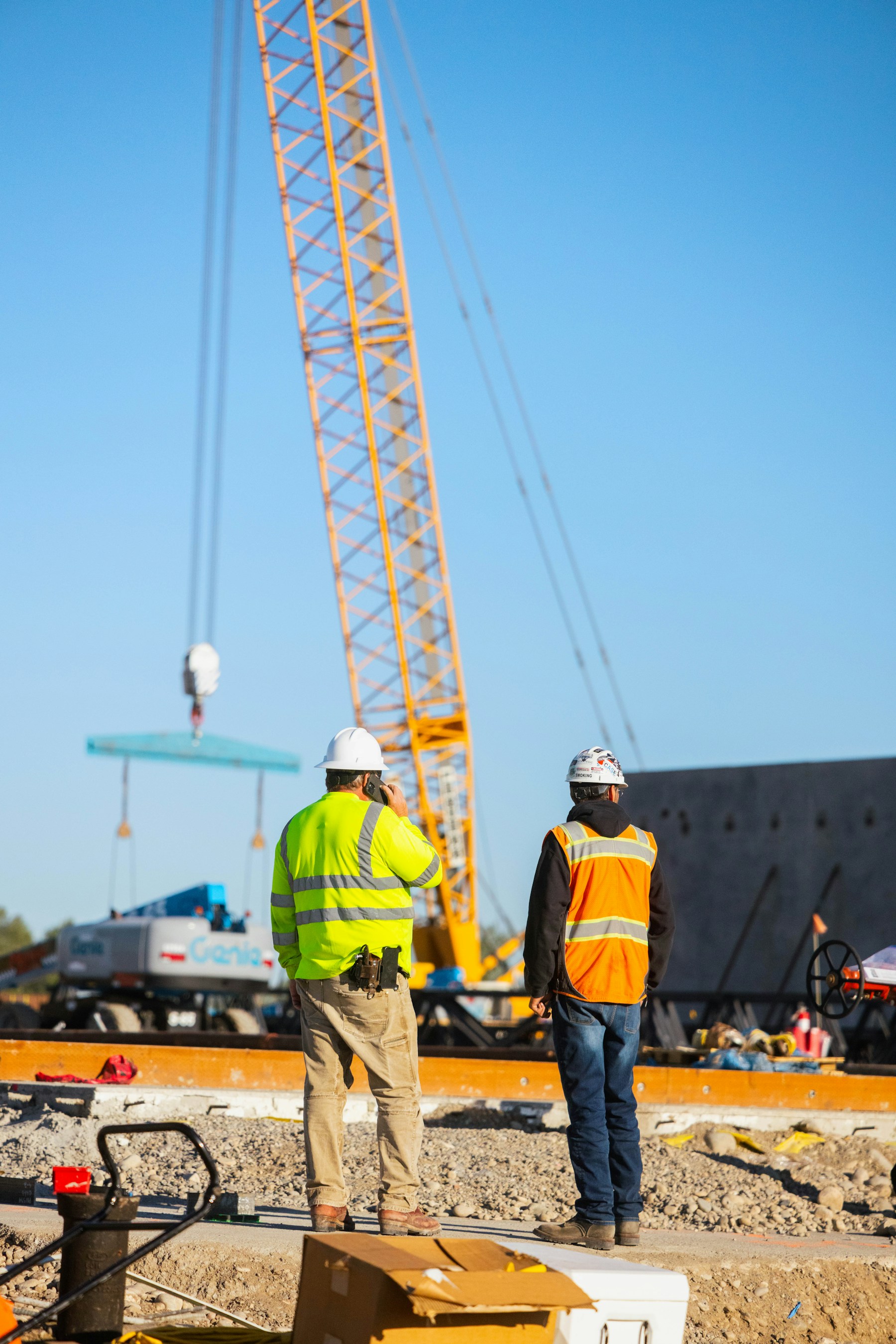 Construction workers on site observing a crane lifting materials into place